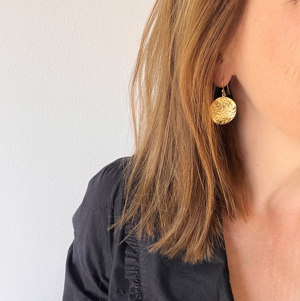 Hammered coin earrings in gold on model