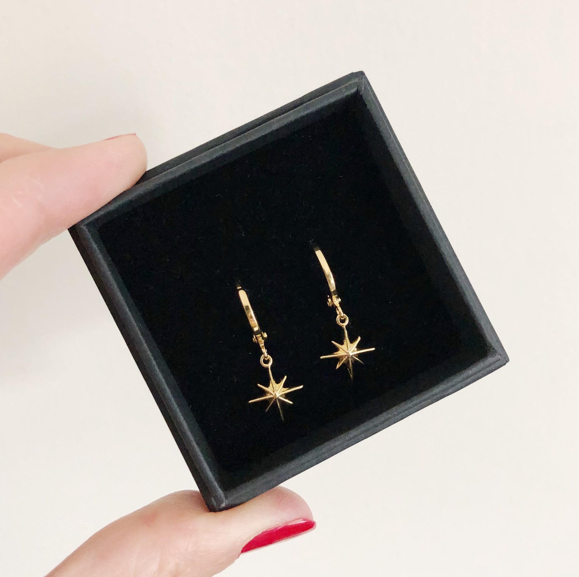 Tiny hoop earrings with a star charm in gold